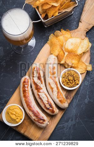 Grilled german sausages with mustard and fried potato chips