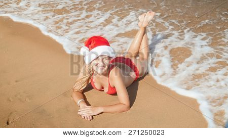 Cheerful Smiling Young Woman Wearing Santa S Hat Enjooying Lying On Th Esea Beach. Concept Of Travel