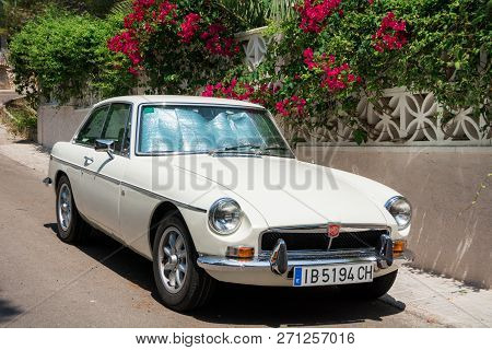 Santa Ponsa, Mallorca, Spain - July 24, 2013:  Retro Car Mg Bgt Is Parked Near A Wall With Flowers A