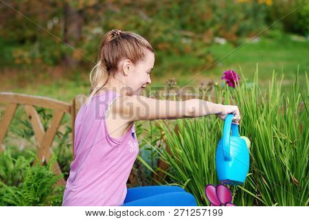 Smiling Caucasian Woman Watering Plants And Flowers With Water Can On A Croft.