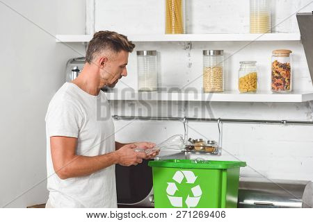 Adult Man Putting Empty Plastic Bottle In Green Recycle Box