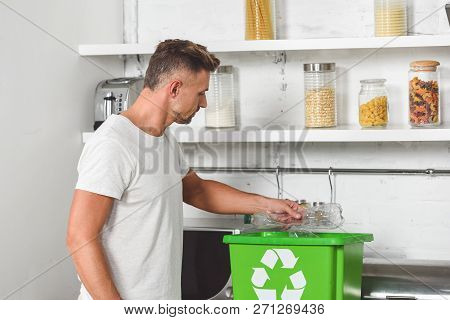 Handsome Man Putting Empty Plastic Bottle In Green Recycle Box
