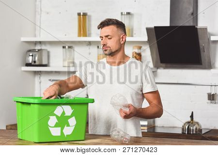 Handsome Man Putting Plastic Bottles In Green Recycle Box