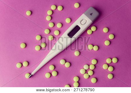 Small Medical Pharmacetic Round Pills, Vitamins, Drugs And Electronic Digital Thermometer On A Pink 