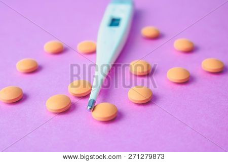 Small Medical Pharmacetic Round Pills, Vitamins, Drugs And Electronic Digital Thermometer On A Pink 