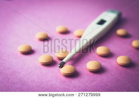 Small Medical Pharmacetic Round Pills, Vitamins, Drugs And Electronic Digital Thermometer On A Pink 