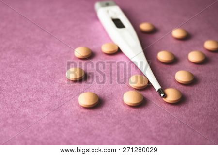 Small Medical Pharmacetic Round Pills, Vitamins, Drugs And Electronic Digital Thermometer On A Pink 