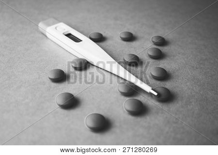 Small Medical Pharmaceptic Round Pills, Vitamins, Drugs And Electronic Digital Thermometer On A Blac
