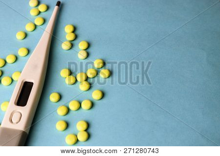 Small Medical Pharmacetic Round Tablets, Vitamins, Drugs And Electronic Digital Thermometer On A Blu