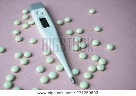 Small Medical Pharmacetic Round Pills, Vitamins, Drugs And Electronic Digital Thermometer On A Pink 