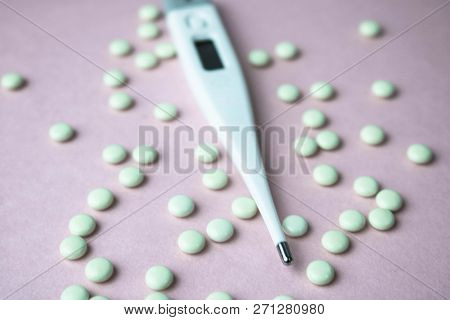 Small Medical Pharmacetic Round Pills, Vitamins, Drugs And Electronic Digital Thermometer On A Pink 