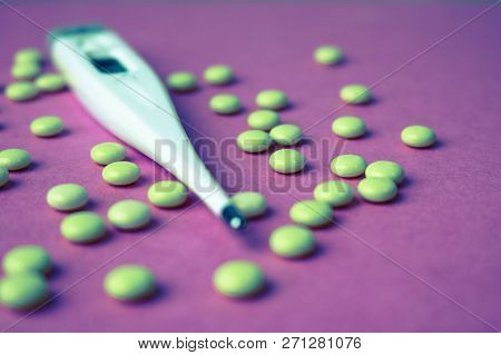 Small Medical Pharmacetic Round Pills, Vitamins, Drugs And Electronic Digital Thermometer On A Pink 