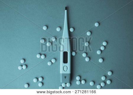 Small Medical Pharmacetic Round Tablets, Vitamins, Drugs And Electronic Digital Thermometer On A Blu