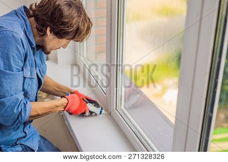 Man In A Blue Shirt Does Window Installation