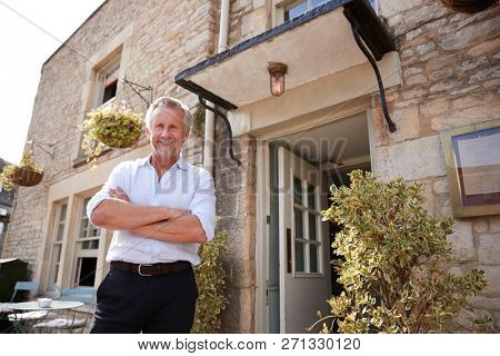 Senior male restaurant pub owner stands outside the entrance