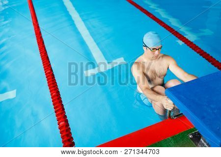 Image of sportive swimmer man in blue cap at side in pool