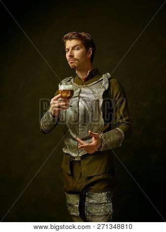 Medieval Knight With Beer On Dark Studio Background. Portrait In Low Key Of Brutal Man In Tradishion