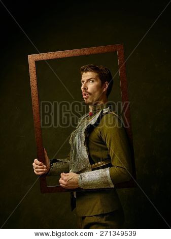 Medieval Knight On Dark Studio Background. Portrait In Low Key Of Brutal Man In Tradishional Retro C