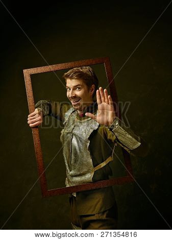 Medieval Knight On Dark Studio Background. Portrait In Low Key Of Brutal Man In Tradishional Retro C