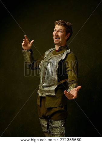 Medieval Happy Knight On Dark Studio Background. Portrait In Low Key Of Brutal Man In Tradishional R