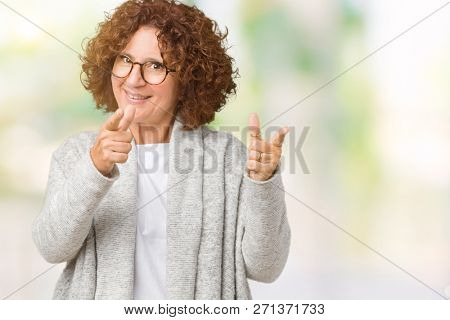 Beautiful middle ager senior woman wearing jacket and glasses over isolated background pointing fingers to camera with happy and funny face. Good energy and vibes.