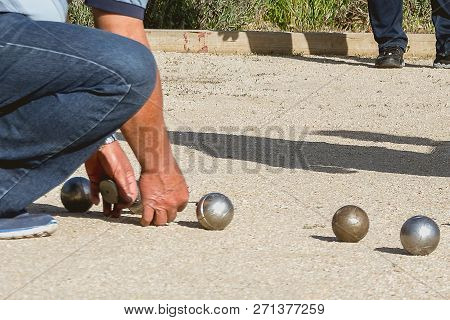 Senior People Measuring Distance In Petanque Game In A Park Outside