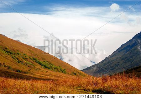 Landscape - View From The Mountain Pass On A Sunny Day To The Valley Hidden By Low Clouds