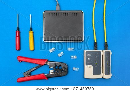Cripmer Tool, Network Cable Tester And A Switch Router Isolated On The Blue Background. Network Mait