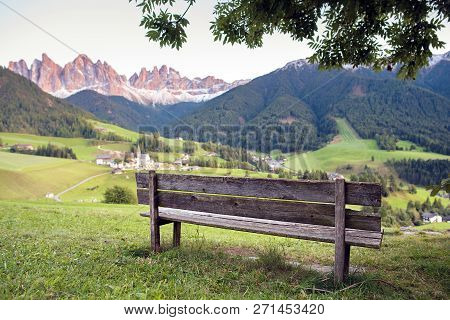 Bench With Alpine Village And Mountains On Background