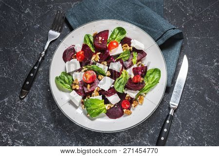 Dish With A Salad Of Feta, Beetroot, Cherry Tomatoes And Walnuts On A Stone Background.