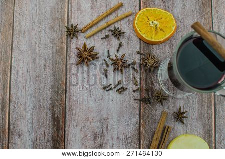 Hot Mulled Wine Drink With Lemon, Apple, Cinnamon, Anise And Other Spices In A Glass Cup Between Fir
