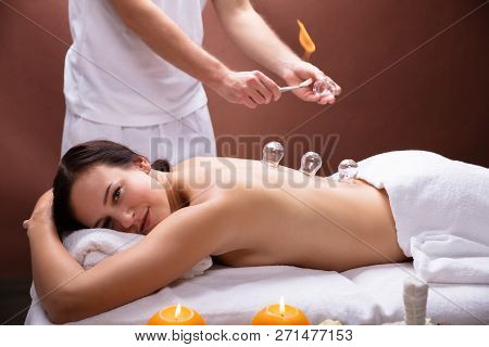 Male Therapist Giving Cupping Therapy To Young Woman In Spa