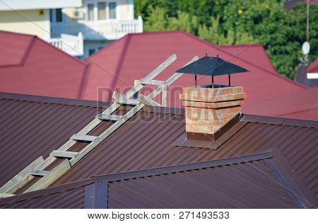 Wooden Stairs On A Metal Gable Roof Near The Brick Chimney