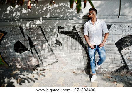 Stylish Tall Arabian Man Model In White Shirt, Jeans And Sunglasses Posed At Street Of City. Beard A