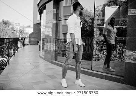 Stylish Tall Arabian Man Model In White Shirt, Jeans And Sunglasses Posed At Street Of City. Beard A