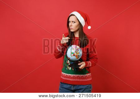 Strict Young Santa Girl In Christmas Hat Holding World Globe Pointing Index Finger On Camera Isolate