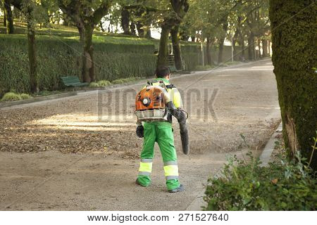 Gardener With Blower Backpack Working In City Park , Blowing Leafs. Autumn Concept