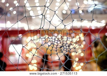 In Selective Focus Of Black Spider Web Ropes With Colorful Bokeh Light At Night Background
