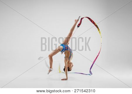 The Portrait Of Beautiful Young Brunette Woman Gymnast Training Calilisthenics Exercise With Blue Ri