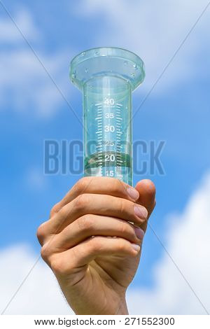 Hand Holding Filled Water Meter Up In Blue Sky With Clouds