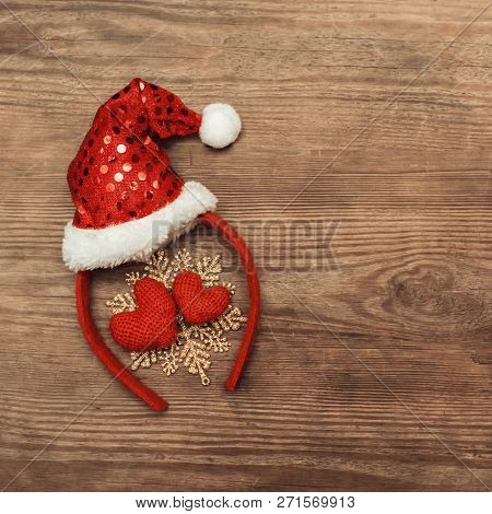 Background Christmas Decoration Red Cap Of Santa And Two Hearts On Wooden Table.