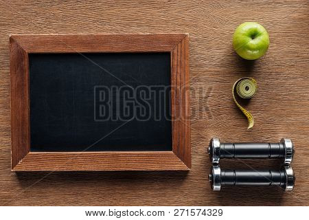 Top View Of Blank Wooden Chalk Board, Apple, Dumbbells And Measuring Tape, Dieting And Healthy Lifes