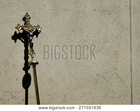 Golden Holy Processional Cross Leaning On A Concrete Wall With Shadow Copy Space