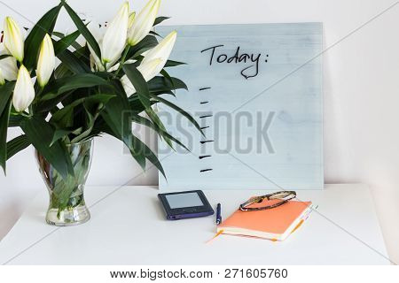 Orange Notebook, Glassses, Blue E-book With Plans For Today Desk And A Bouquet Of Beautiful White Li