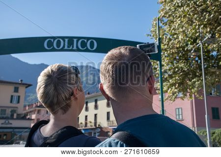 Two People, A Man And A Woman Looking At The City Of Colico In Italy On A Windy Day