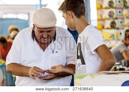 Turkish Man Is Paying A Boy For The Food That He Just Bought At Bazaar - Seferihisar, Izmir, Turkey 