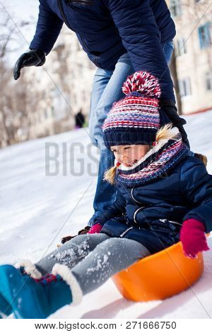 Winter Family Fun Of Father With Daugther, Sliding Down The Snow Hill, Happy Little Girl Is Laugthin