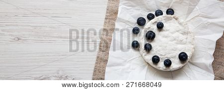 Camembert Cheese In Paper On A White Wooden Background, Overheadview. Food For Wine. Copy Space.