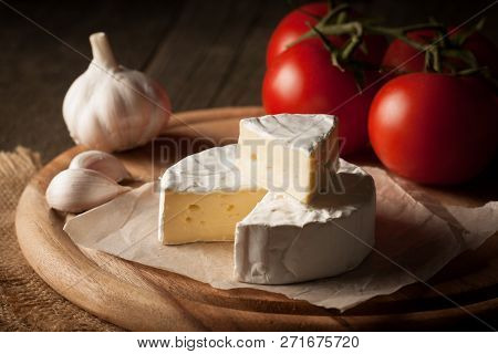 Camembert And Brie Cheese On Wooden Background With Tomatoes, Letuce And Garlic. Italian Food. Dairy