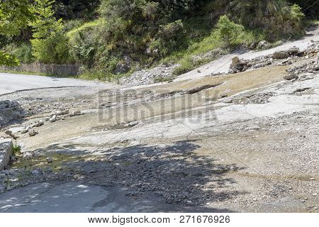 Problems On The Road. Rural, Narrow Road Damaged By A River Flowing Through It In Summer.